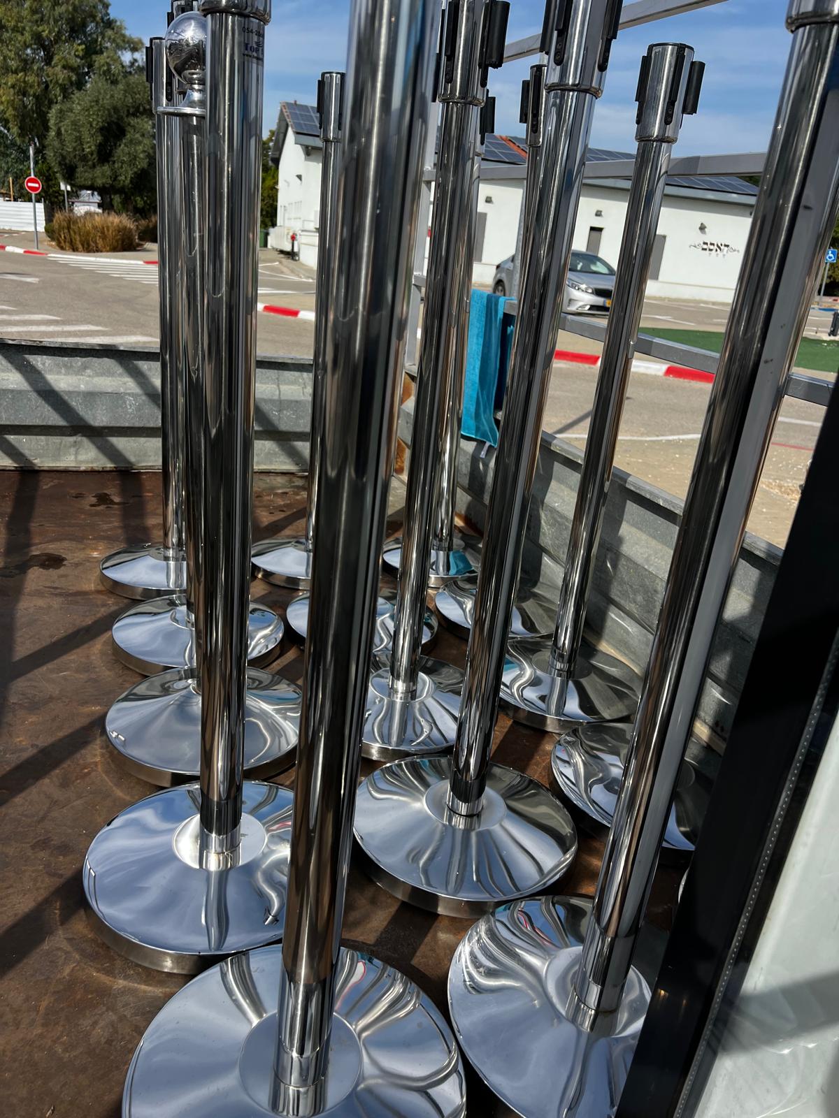 קבוצת עמודי חבלול כסופים מנירוסטה (מיועדים לתיחום קהל) מועמסים על נגרר הובלה בדרך לאירוע.