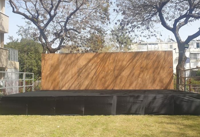 במה להשכרה בכפר סבא, מוקמת על דשא בפארק, עם חיפוי שחור וגב במה מעץ.